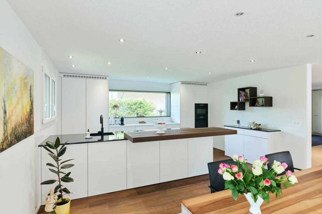 Weisse Küche mit Holzakzenten und Halbinsel in Laupen